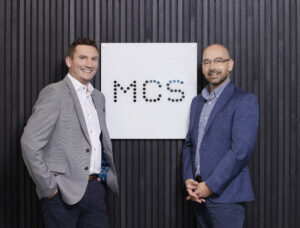 Martyn and Stephen in front of MCS logo.