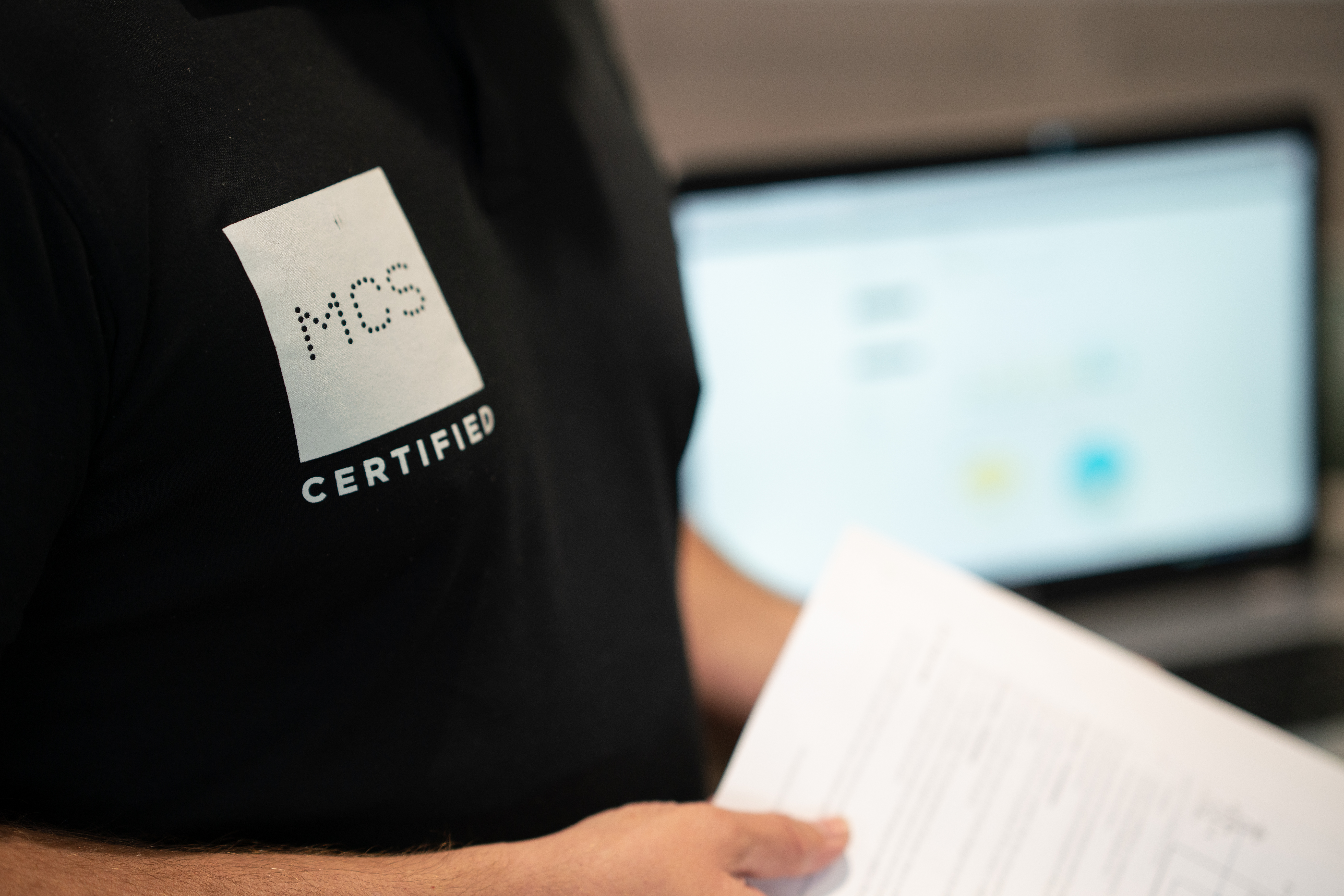 MCS certified polo shirt in front of laptop.