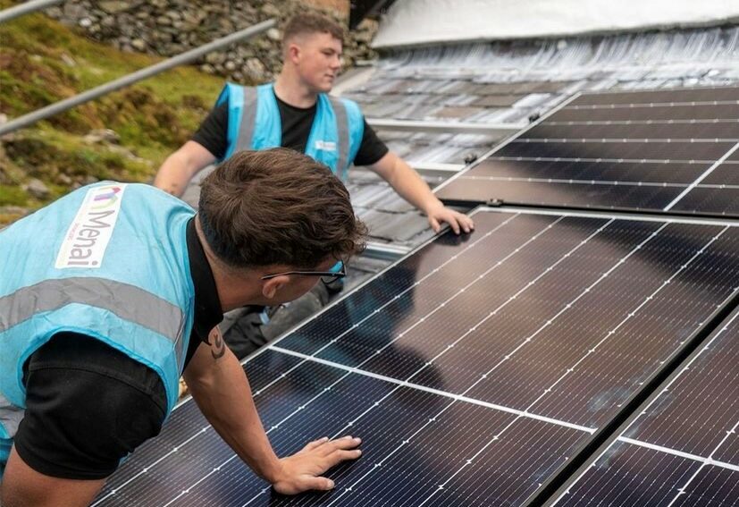 Two installers from Menia heating installing solar panels on roof
