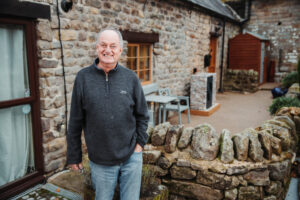 Man outside house, Air Source Heat Pump in back