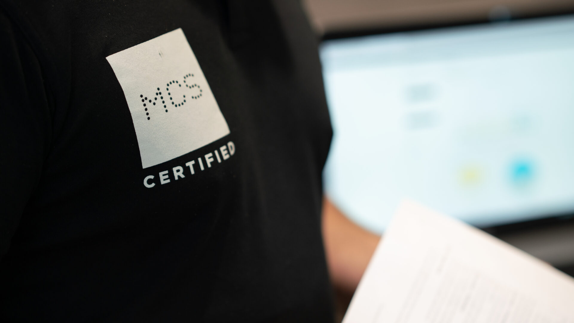 Person wearing MCS certified polo holding sheet of paper.