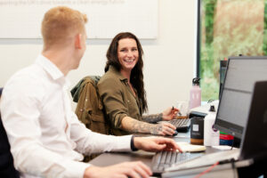 Two MCS employees laughing at their desks.